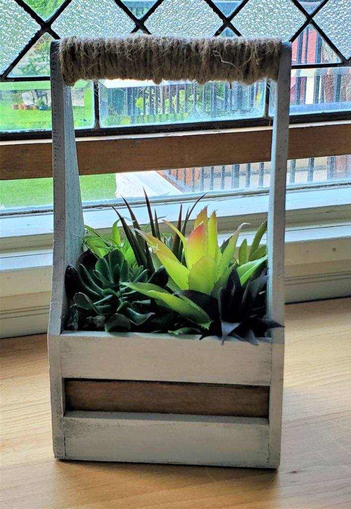 Finished wooden crate full of faux succulents.
